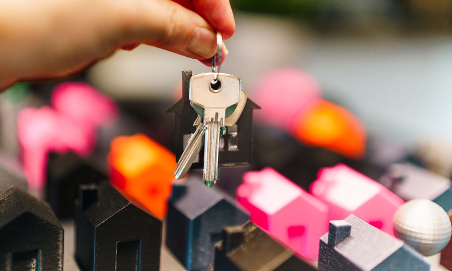 Consórcio vale a pena: casas em miniatura e chaves representando a carta de crédito