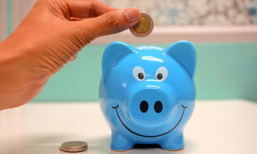 Criança colocando moeda no cofrinho aprendendo com a conta digital para menores