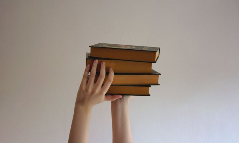 Pessoa segurando pilha de livros sobre o movimento FIRE e independência financeira