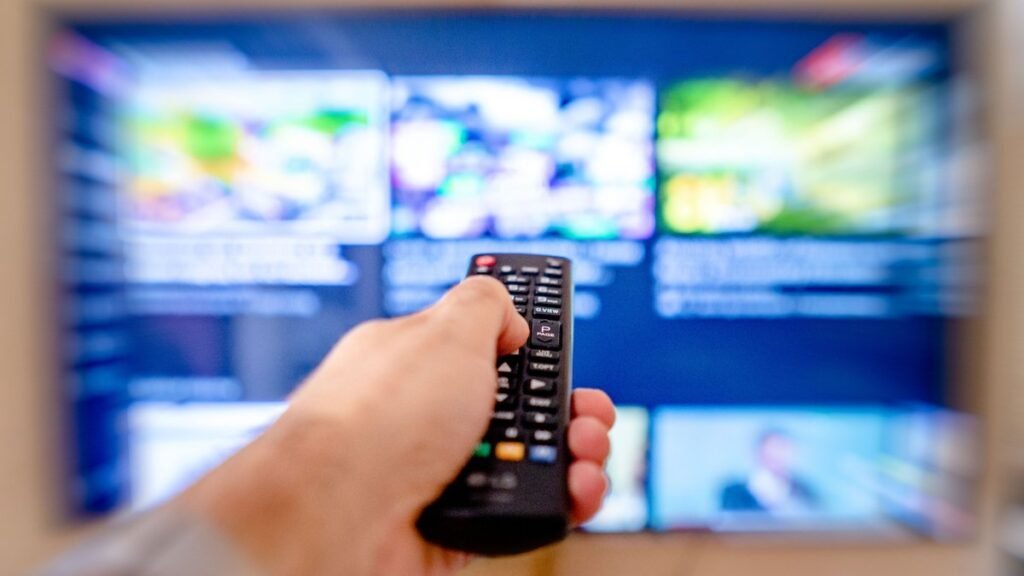 Controle remoto apontado para a TV ao cortar gastos com assinaturas