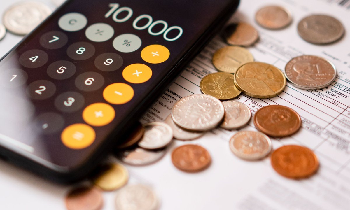 Calculadora e moedas sobre extrato, tema das tarifas em conta digital