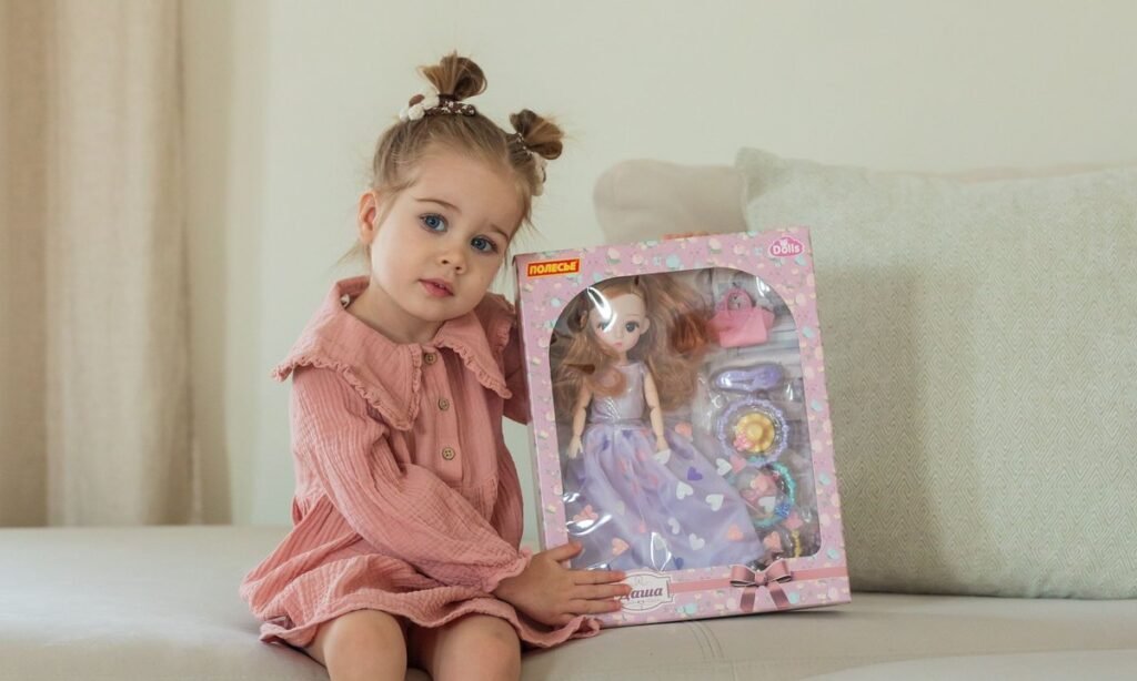 Menina sentada no sofá segurando uma caixa de brinquedo de presente no Dia das Crianças