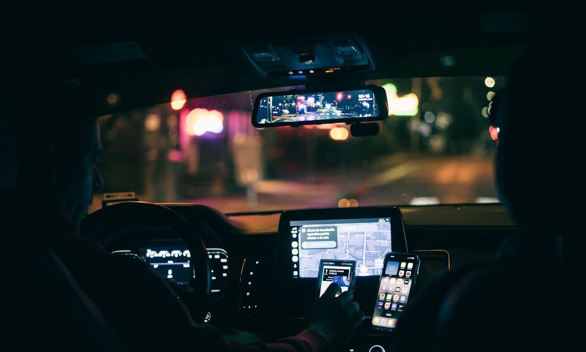 Celular com aplicativo de navegação no painel do carro de um motorista de aplicativo à noite