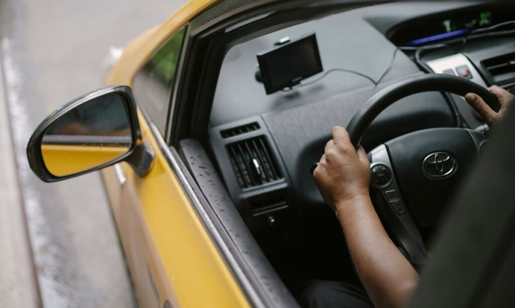 Motorista de aplicativo ao volante de um carro amarelo durante uma corrida