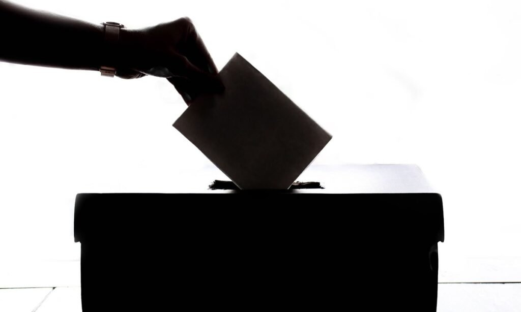 Mão depositando cédula na urna, tema da multa por não votar em 2026