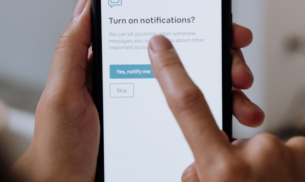 Dedo tocando a tela do celular com pedido para ativar notificações, ideia de bloquear ofertas de crédito