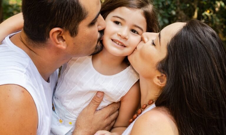 Pai e mãe abraçam a filha, família que pode receber o Bolsa Família de R$ 691
