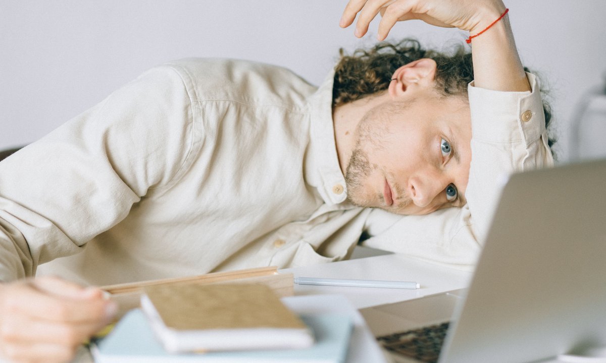 Trabalhador cansado apoiado na mesa diante do notebook, rotina que muda com o fim da escala 6x1