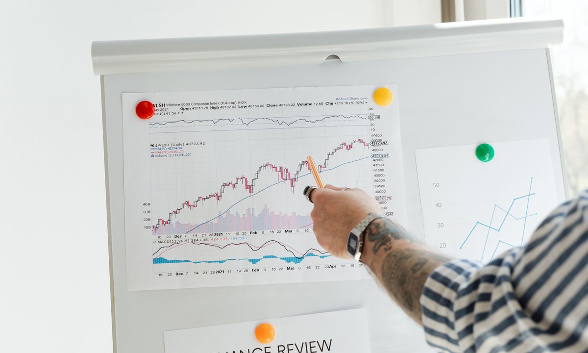 Pessoa apontando gráfico de relatório financeiro em quadro, ilustrando o imposto sobre dividendos 2026