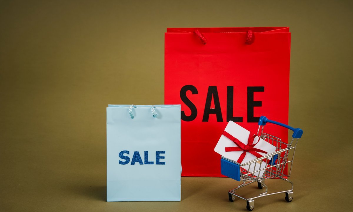Sacolas de compras com a palavra sale e carrinho com presente, ideia de ofertas e promoções