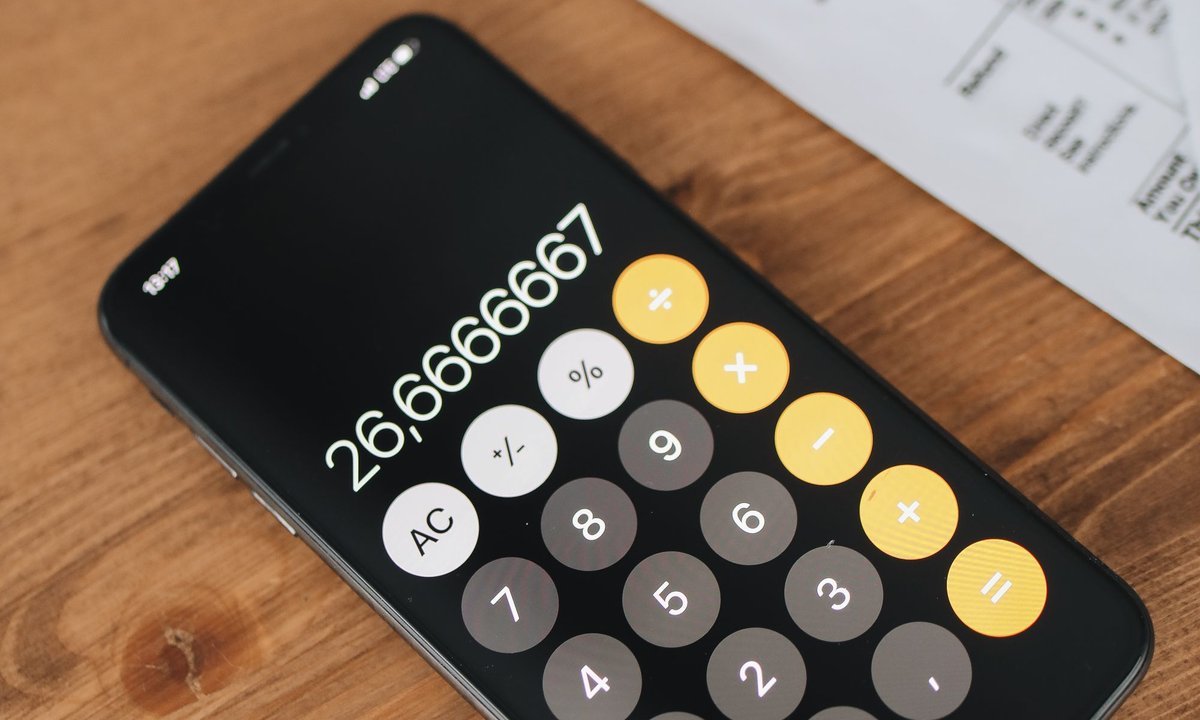 Calculadora no celular sobre a mesa, para decidir entre quitar dívida ou investir