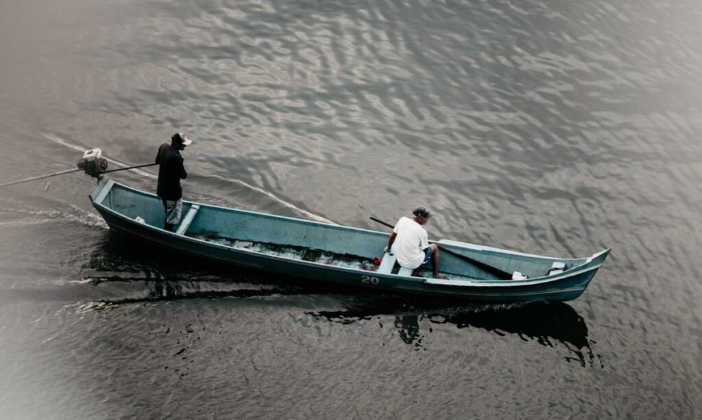 Pescadores artesanais em canoa no rio, beneficiários do seguro-defeso da piracema
