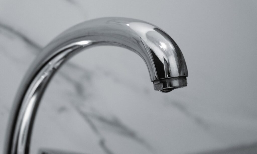 Torneira cromada de cozinha em parede de mármore, símbolo da conta com tarifa social de água